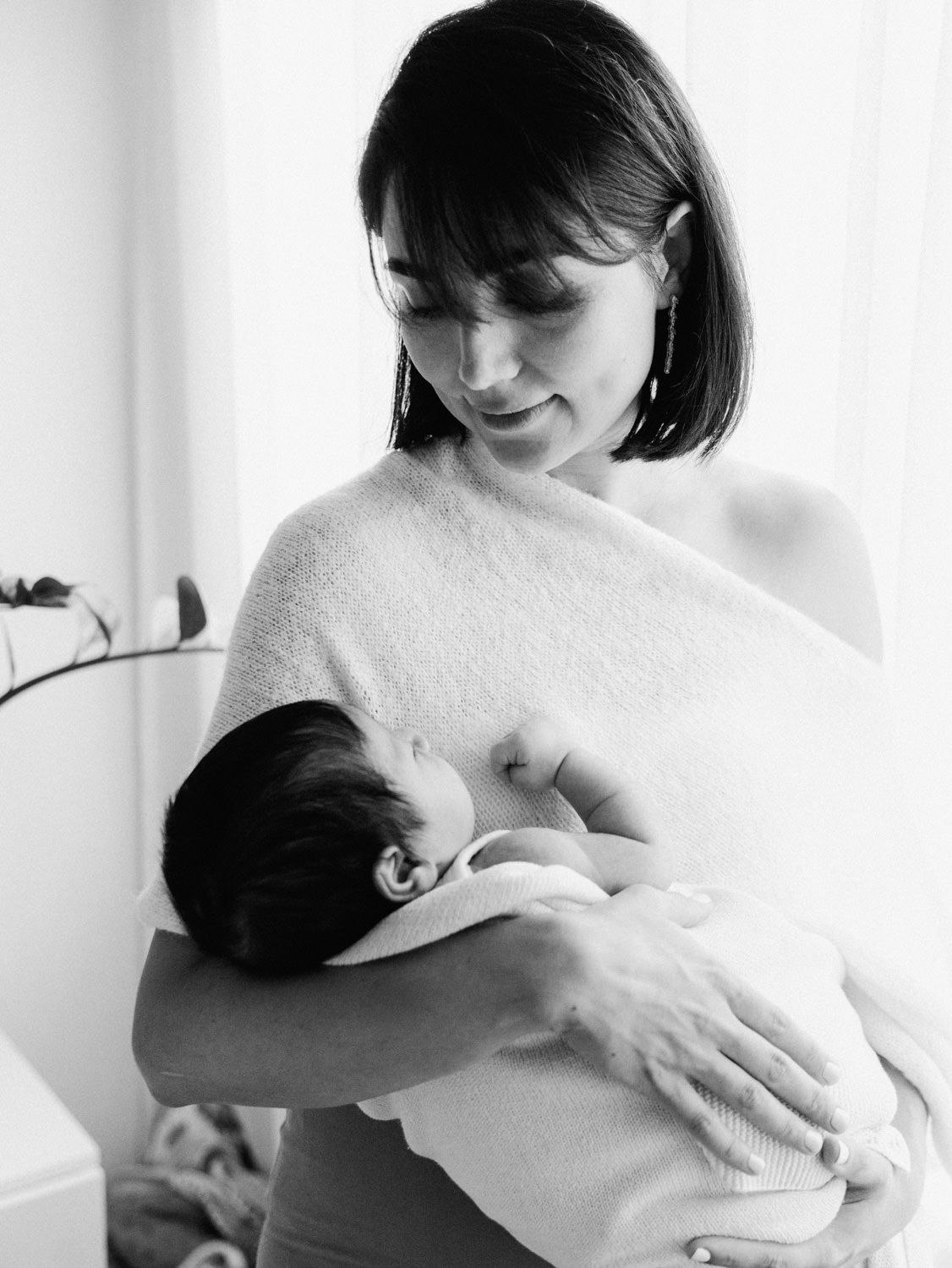 Black and white photo of a mother cradling her newborn baby in her arms.