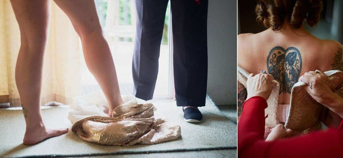 Bride standing on ballet pointe shoes beside groom, with close-up of tattooed back being laced into wedding dress.