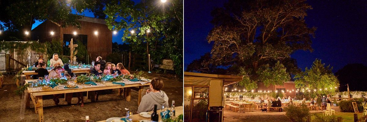 Outdoor evening wedding reception with string lights illuminating guests dining at long wooden tables surrounded by lush greenery.