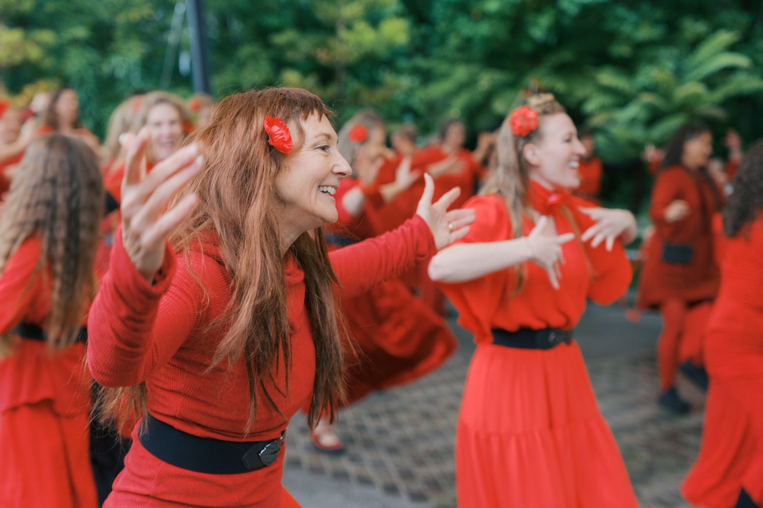 Women in red dresses dancing outdoors in a synchronized group performance.