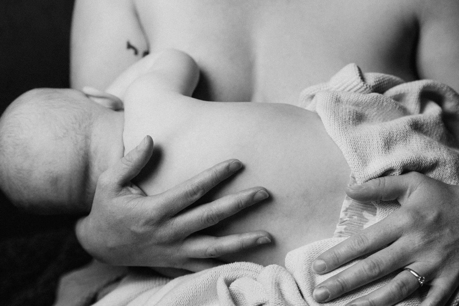 Black and white photo of a mother breastfeeding her newborn baby, cradling the infant tenderly in her arms.