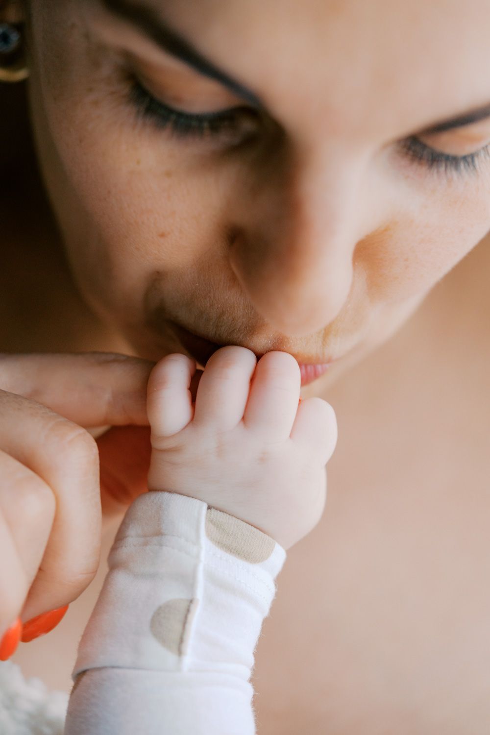 A tender moment as a mother gently kisses her newborn baby's tiny fingers and hand.
