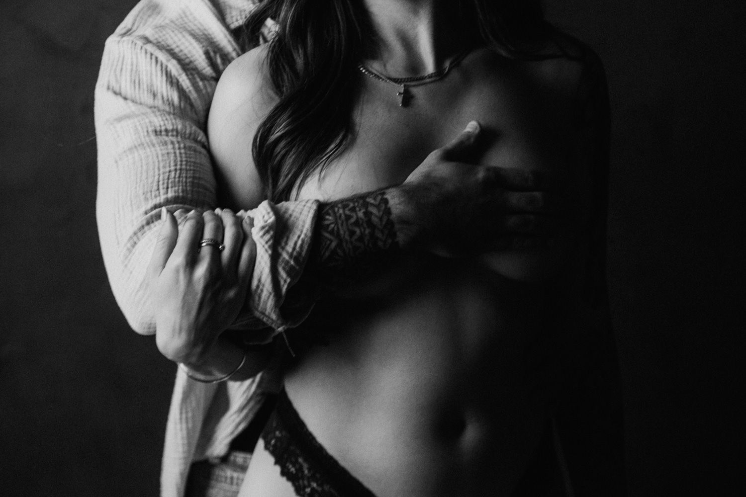 Black and white intimate couple embrace, woman in lace lingerie and open shirt, sensual boudoir photography.
