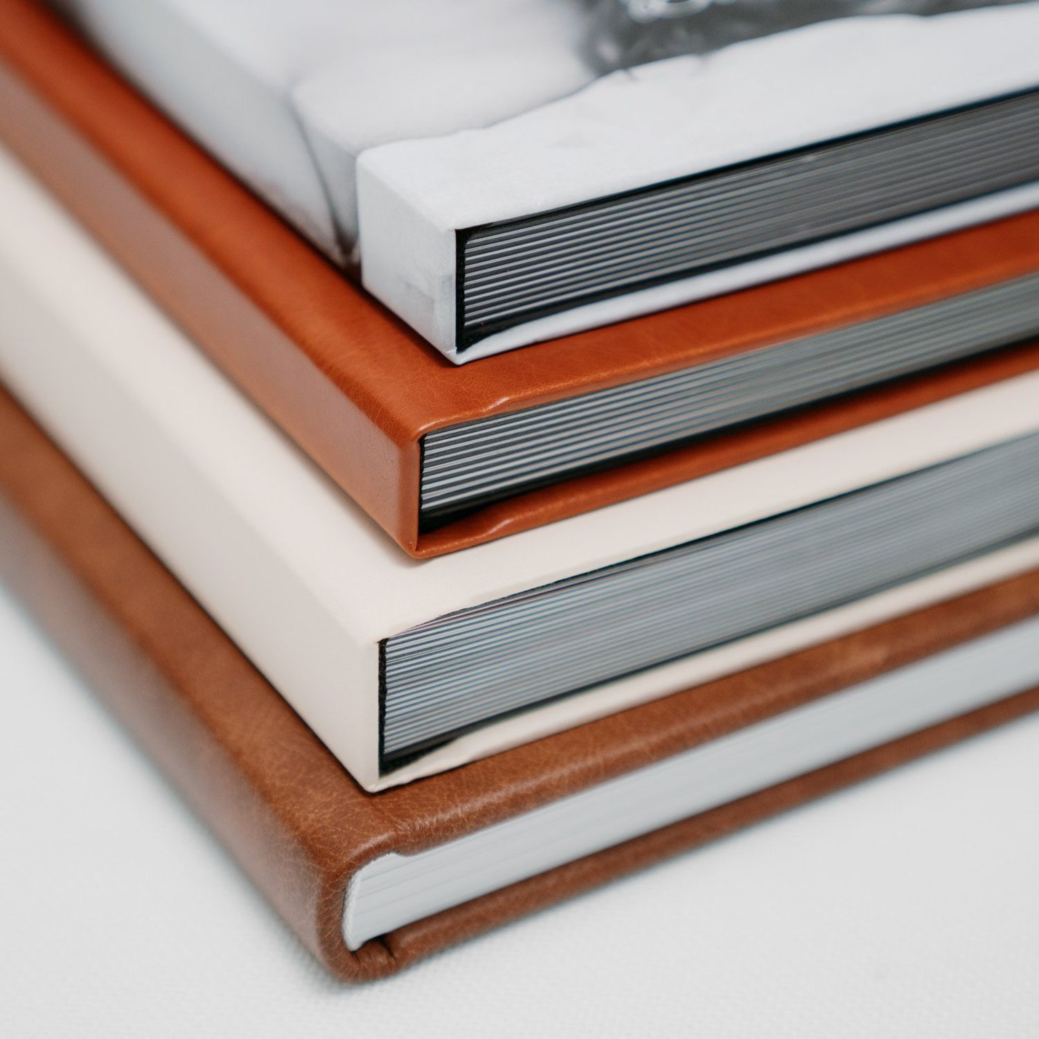 Stack of three leather-bound photo books in tan, cream, and brown, showcasing premium hardcover album designs.