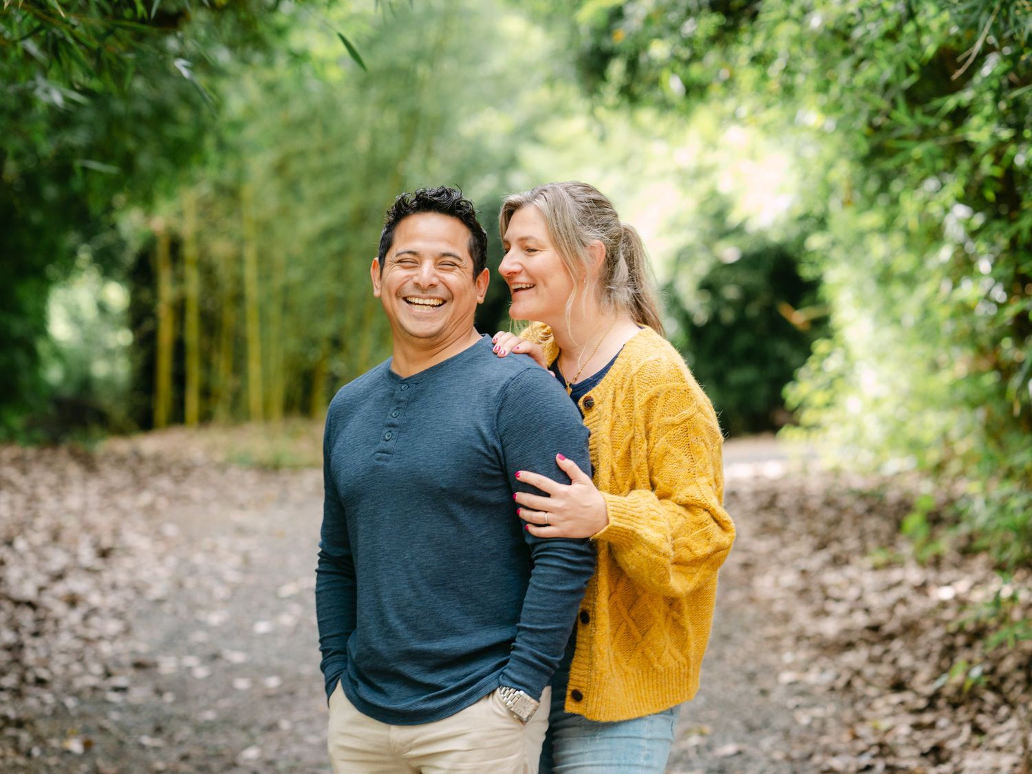 Happy couple embracing on a lush garden path surrounded by bamboo trees and greenery.