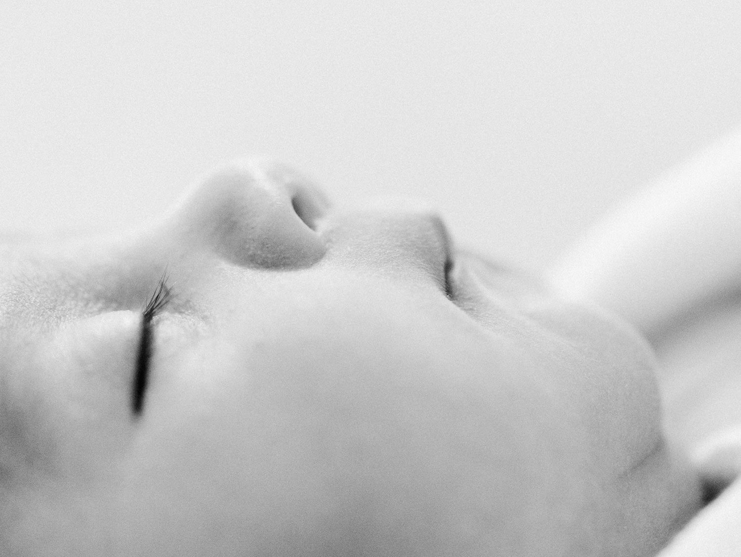 Black and white close-up profile of peaceful sleeping newborn baby's delicate facial features.