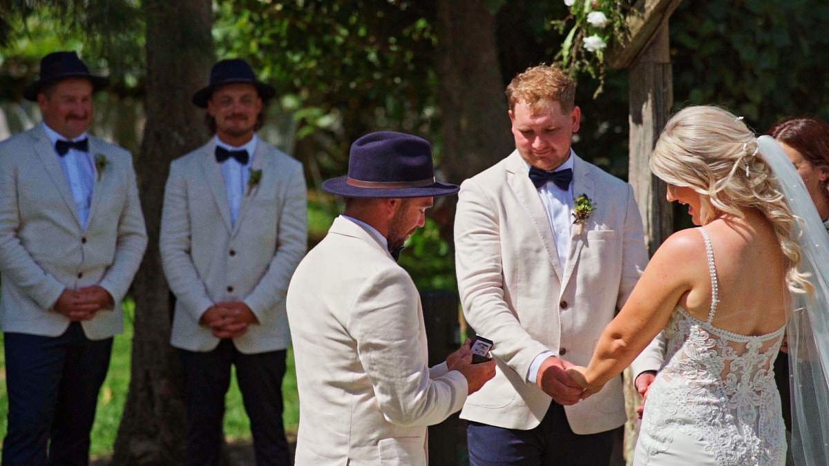 Outdoor wedding ceremony with groom and officiant exchanging vows as groomsmen watch under trees.