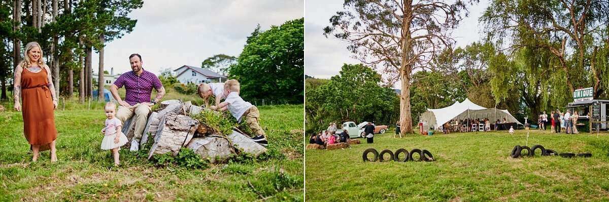 Outdoor wedding reception on lush green lawn with guests near rock feature and white marquee tent with tire decorations.