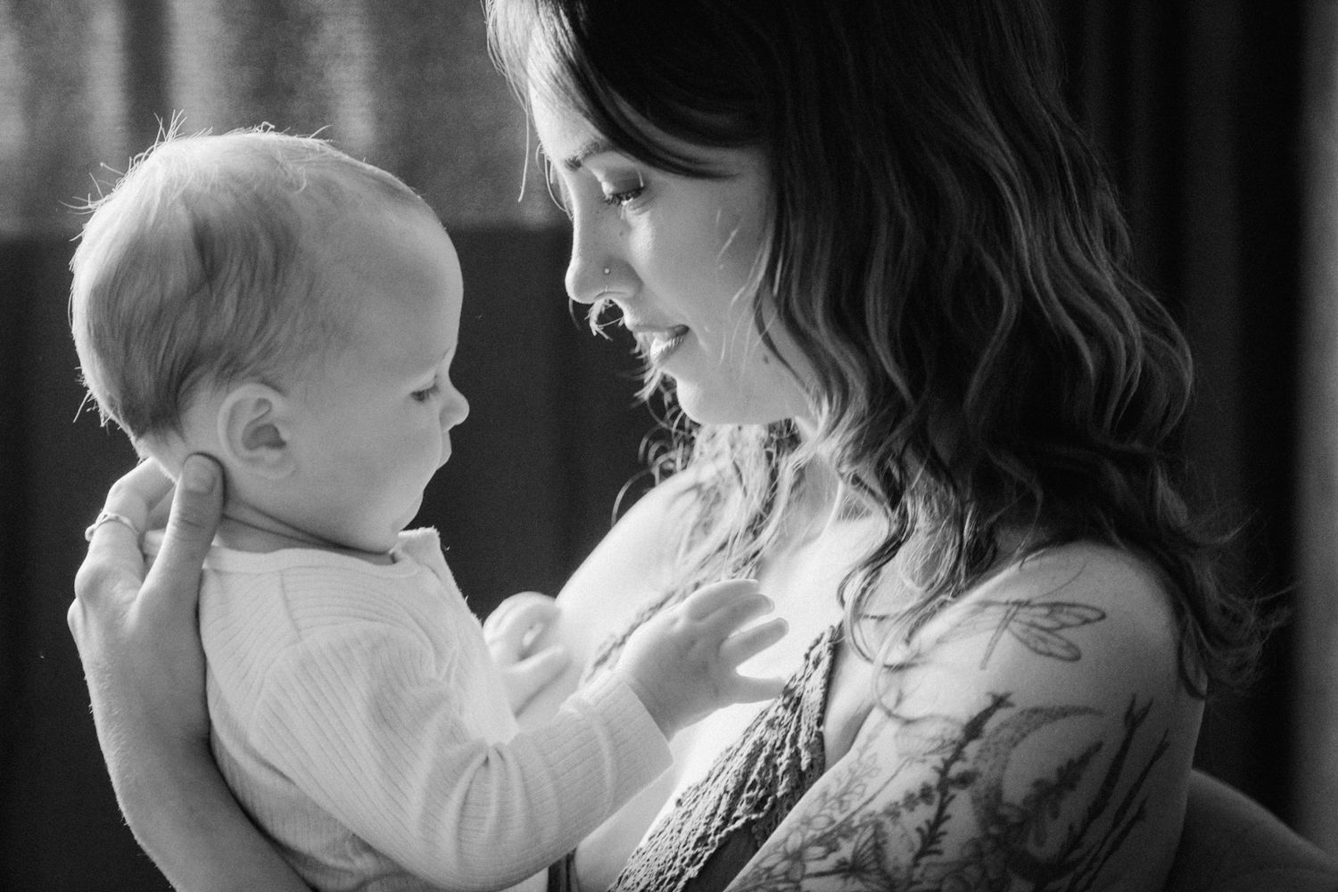 Black and white portrait of a mother tenderly holding and smiling at her baby.