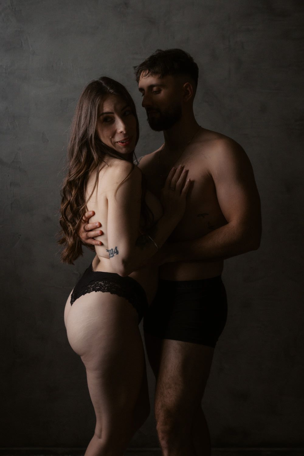 Intimate black and white couples boudoir photo of man and woman embracing in matching black underwear.