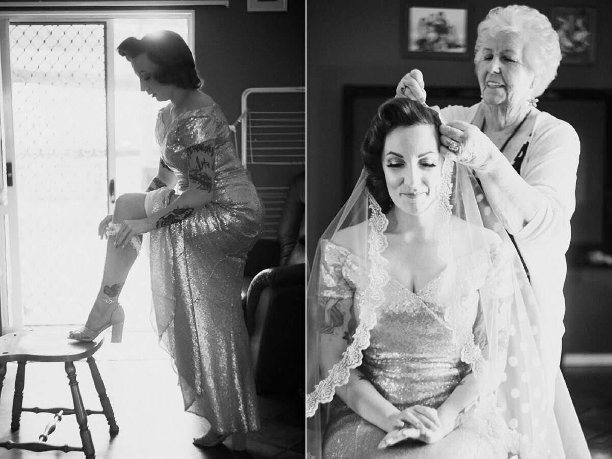Black and white wedding photo of bride getting veil placed by elderly woman and adjusting shoes before ceremony.