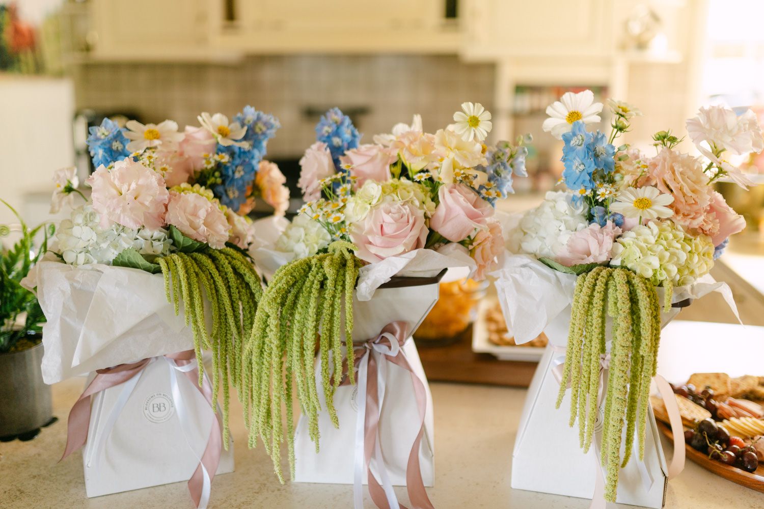 Elegant wedding gift bags adorned with pink roses, blue hydrangeas, and cascading greenery with ribbon.
