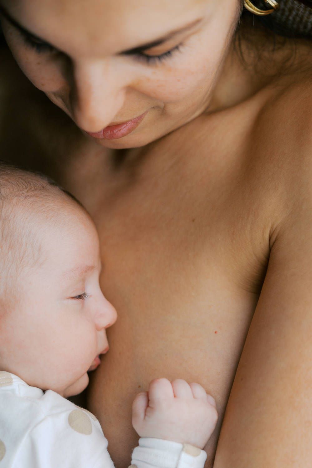 A mother tenderly breastfeeding her newborn baby, sharing a peaceful and intimate bonding moment.