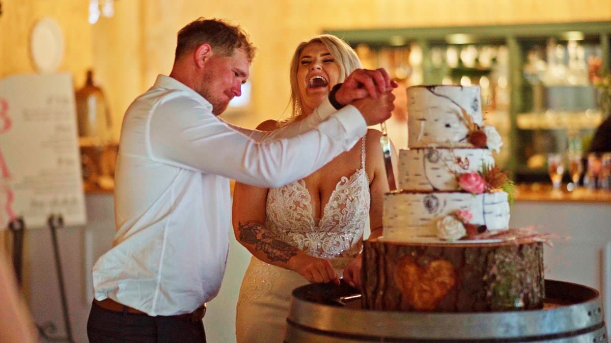 Bride and groom cutting their rustic wedding cake together at a winery reception venue.