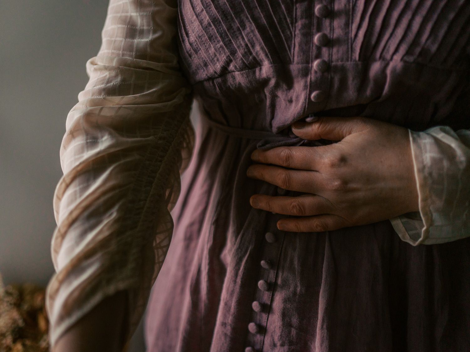 Close-up of two people embracing, wearing vintage Victorian-era purple and white linen dresses with button details.