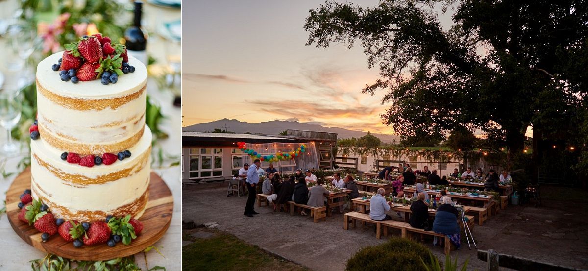 A rustic naked wedding cake topped with fresh berries beside an outdoor reception at sunset with string lights and mountain views.