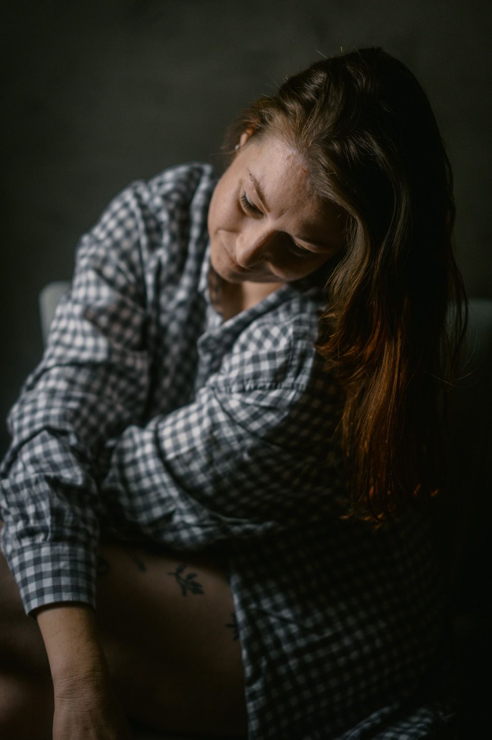Woman in plaid shirt in dramatic dark studio portrait photography.