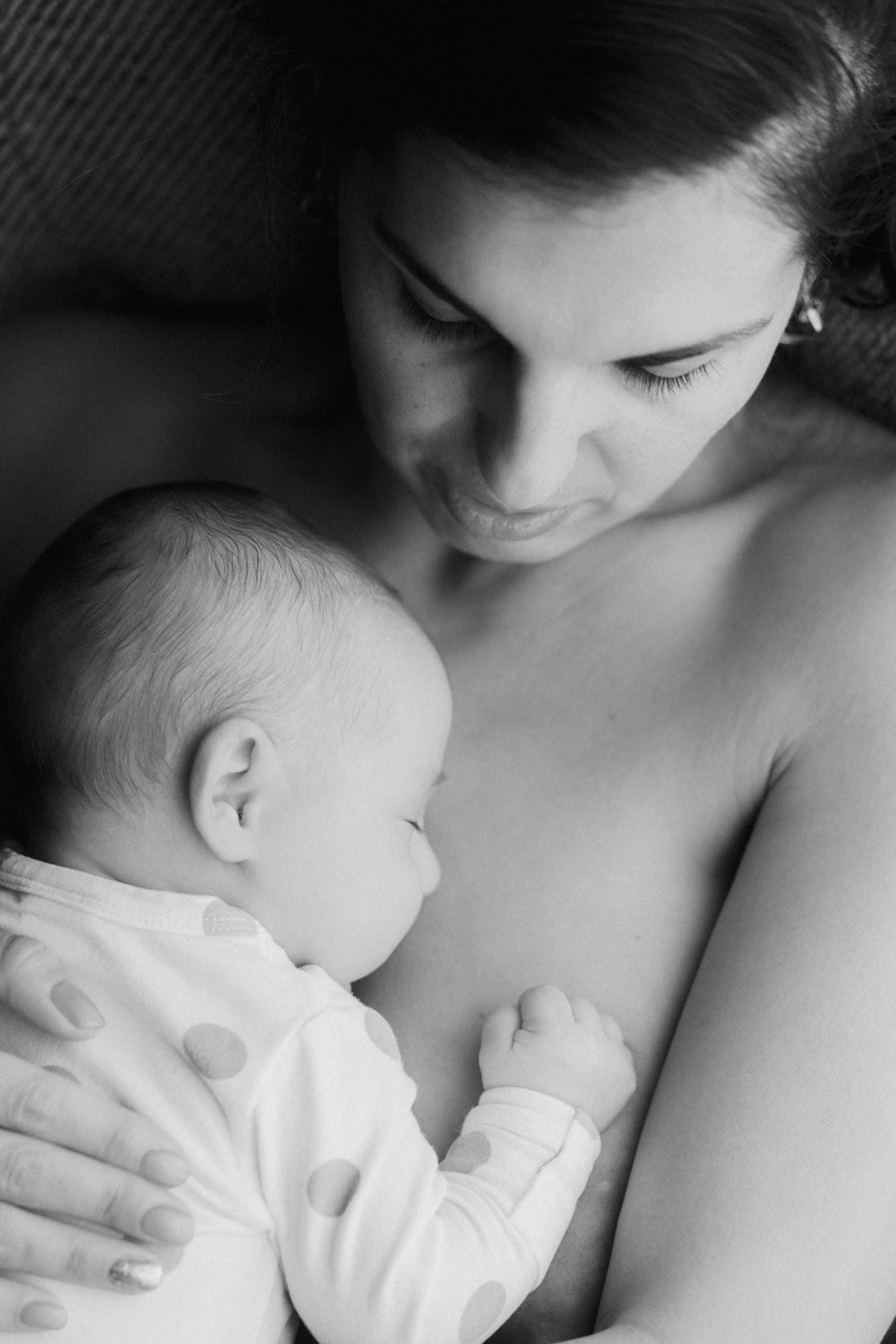 Black and white photo of a mother breastfeeding her newborn baby, sharing a tender bonding moment.