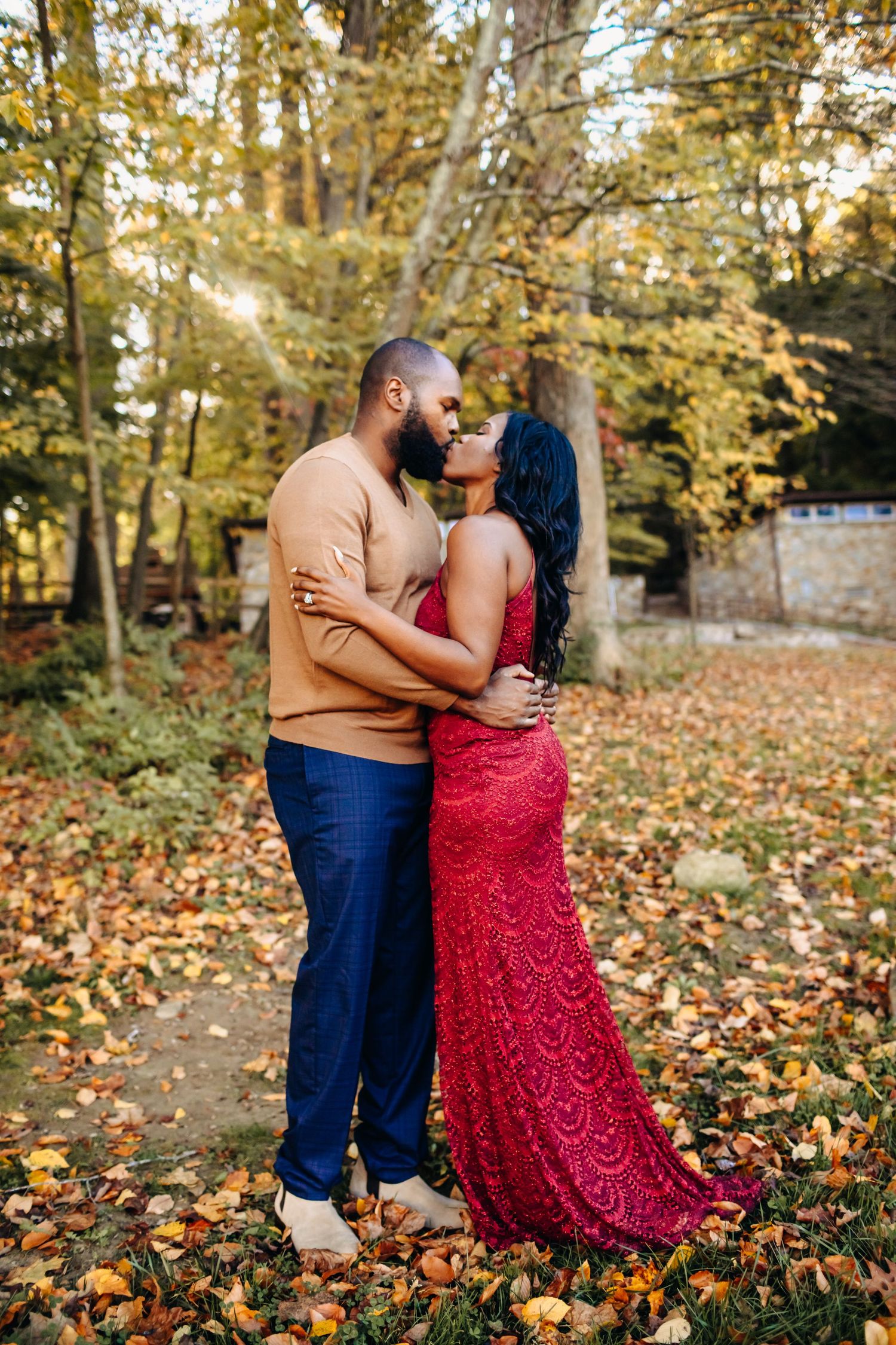 Couple embracing and almost kissing among colorful autumn leaves in a park.