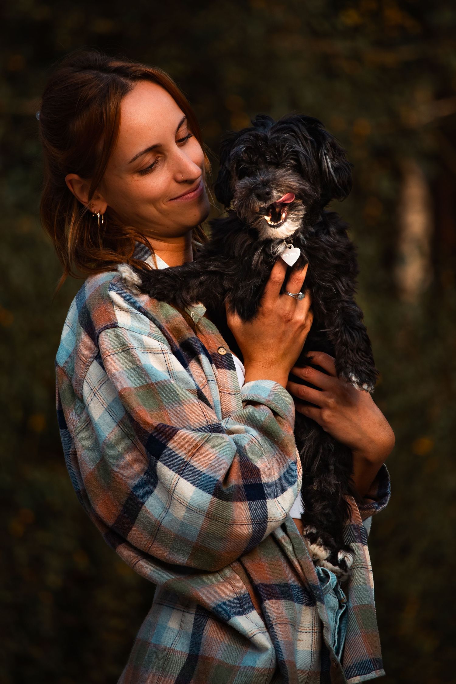 Frau mit Hund auf dem Arm im Wald.