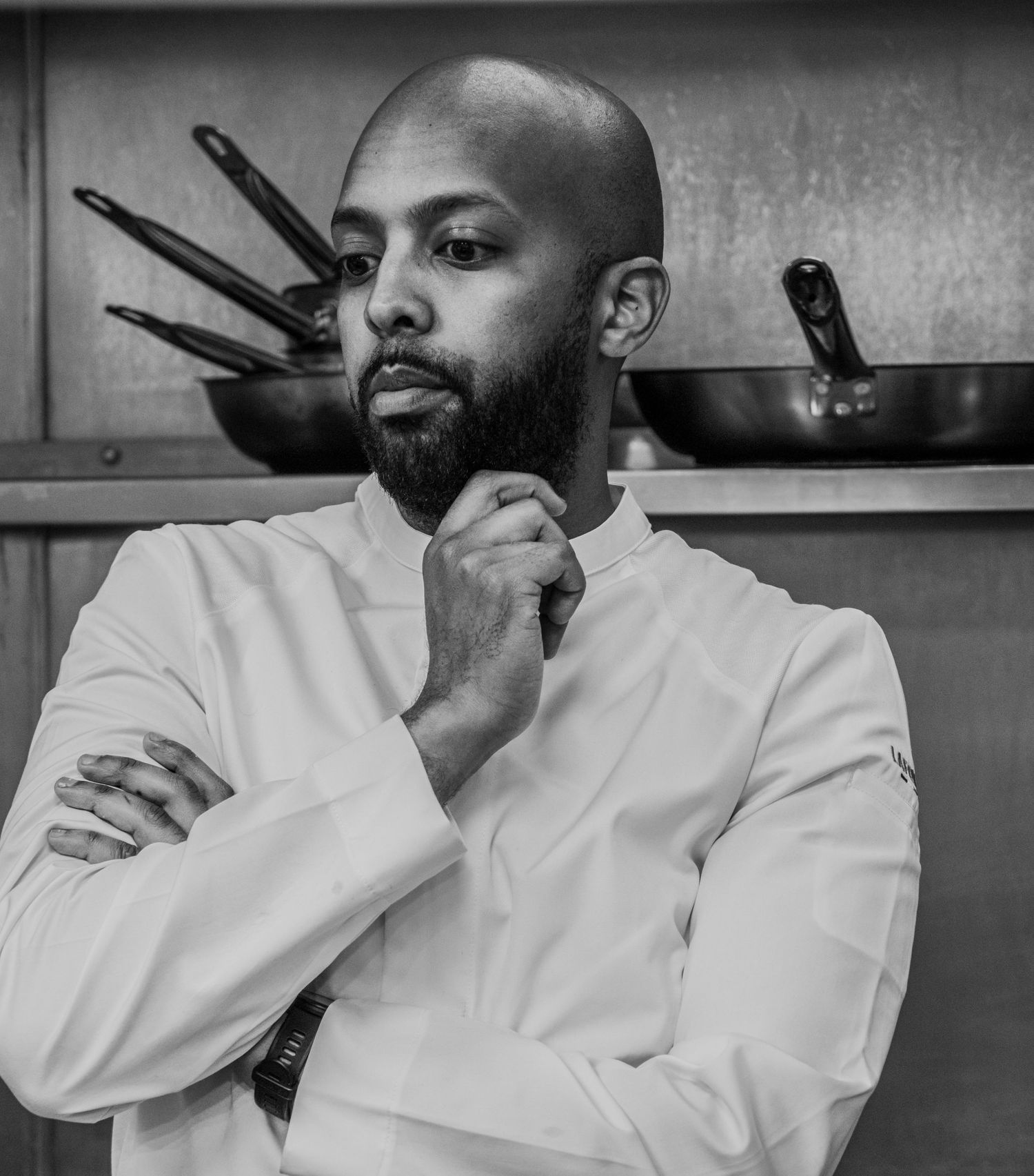 Dramatic high-contrast black and white portrait of a chef studying a dish ahead of service