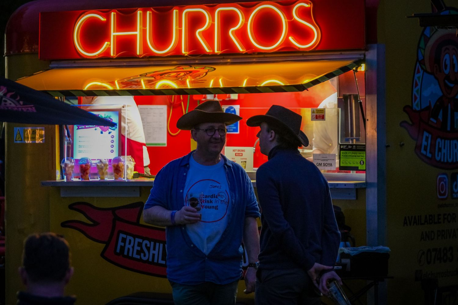 Professional photography by Simon Robertson showing two men standing next to a food vender enjoying a drink.