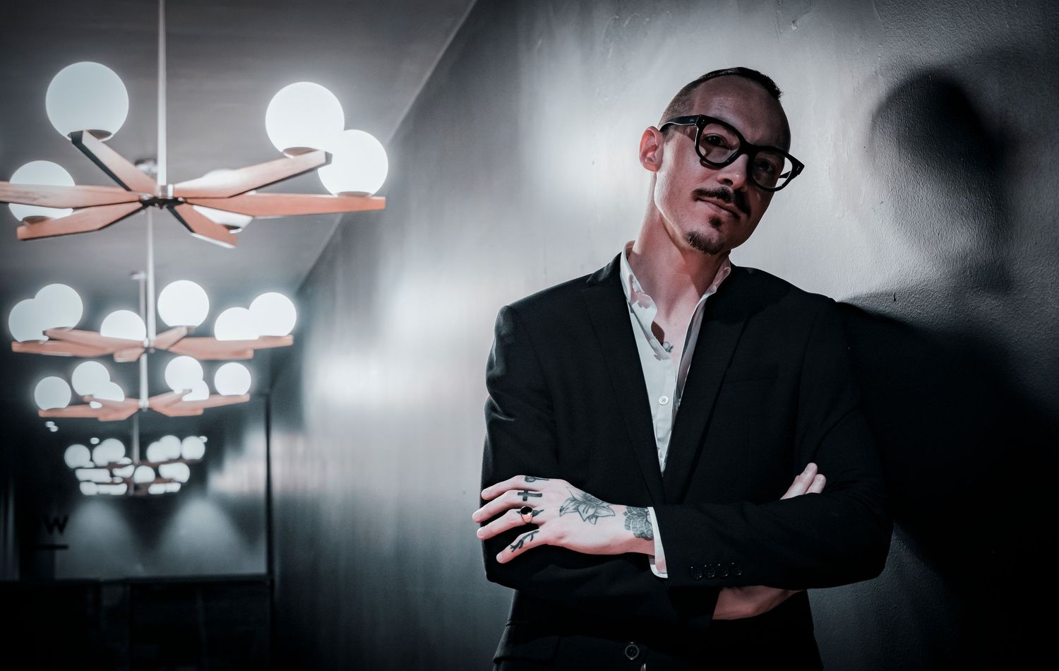Corporate portrait of a male executive leaning thoughtfully against a softly lit office space.