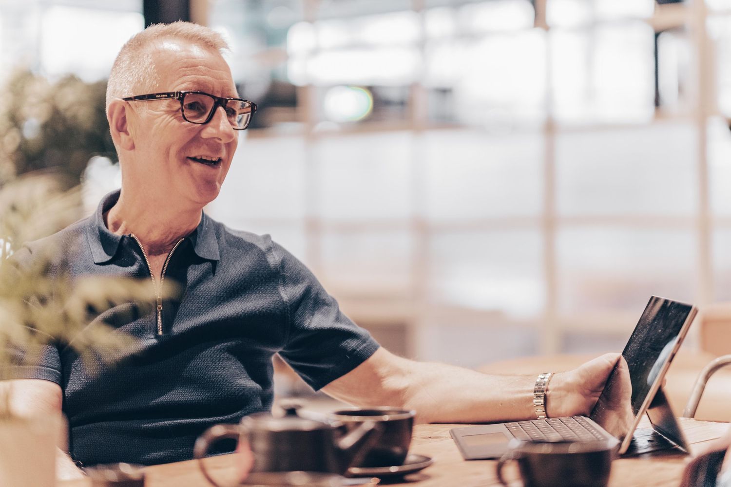 Creative entrepreneur smiling warmly, wearing a casual denim shirt in a bright, modern studio space.