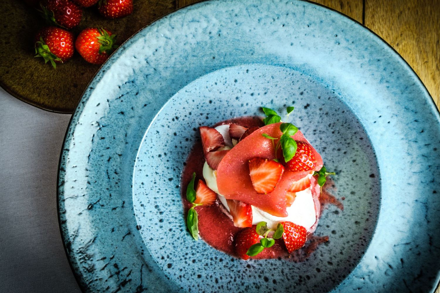 Close-up of bowl of fresh, ripe strawberries with a creamy soft cheese served in a artisan blue bowl.