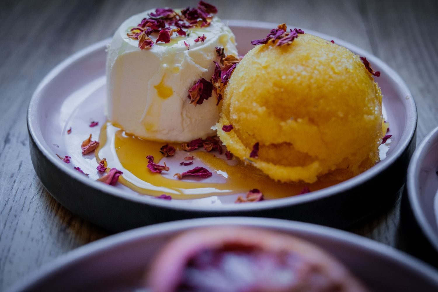 Yellow sorbet beside a cream-coloured dessert topped with flower petals at a Sheffield restaurant, by Simon Robertson.