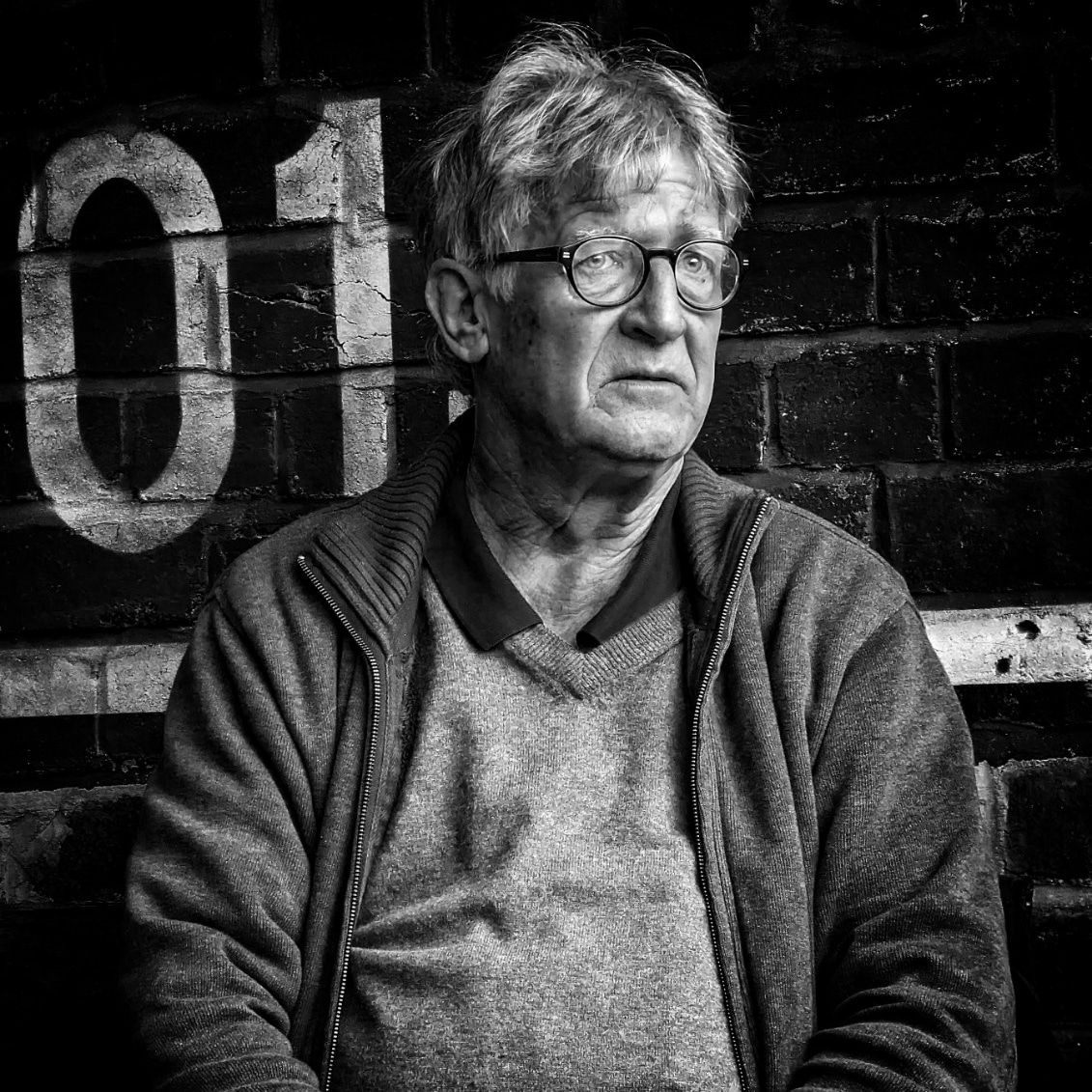 Candid Photograph of a man sitting in a bar by Simon Robertson, capturing a moment with a natural, considered approach.