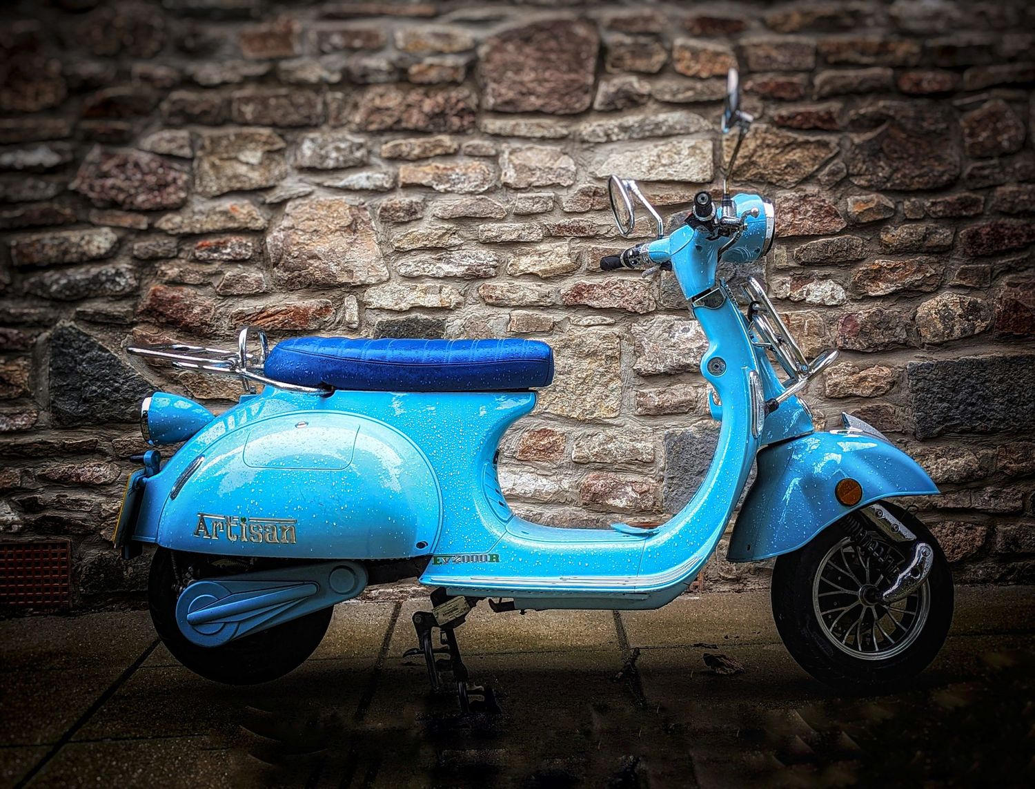 Bright blue vintage scooter parked against a textured stone wall, photographed by Simon Robertson.