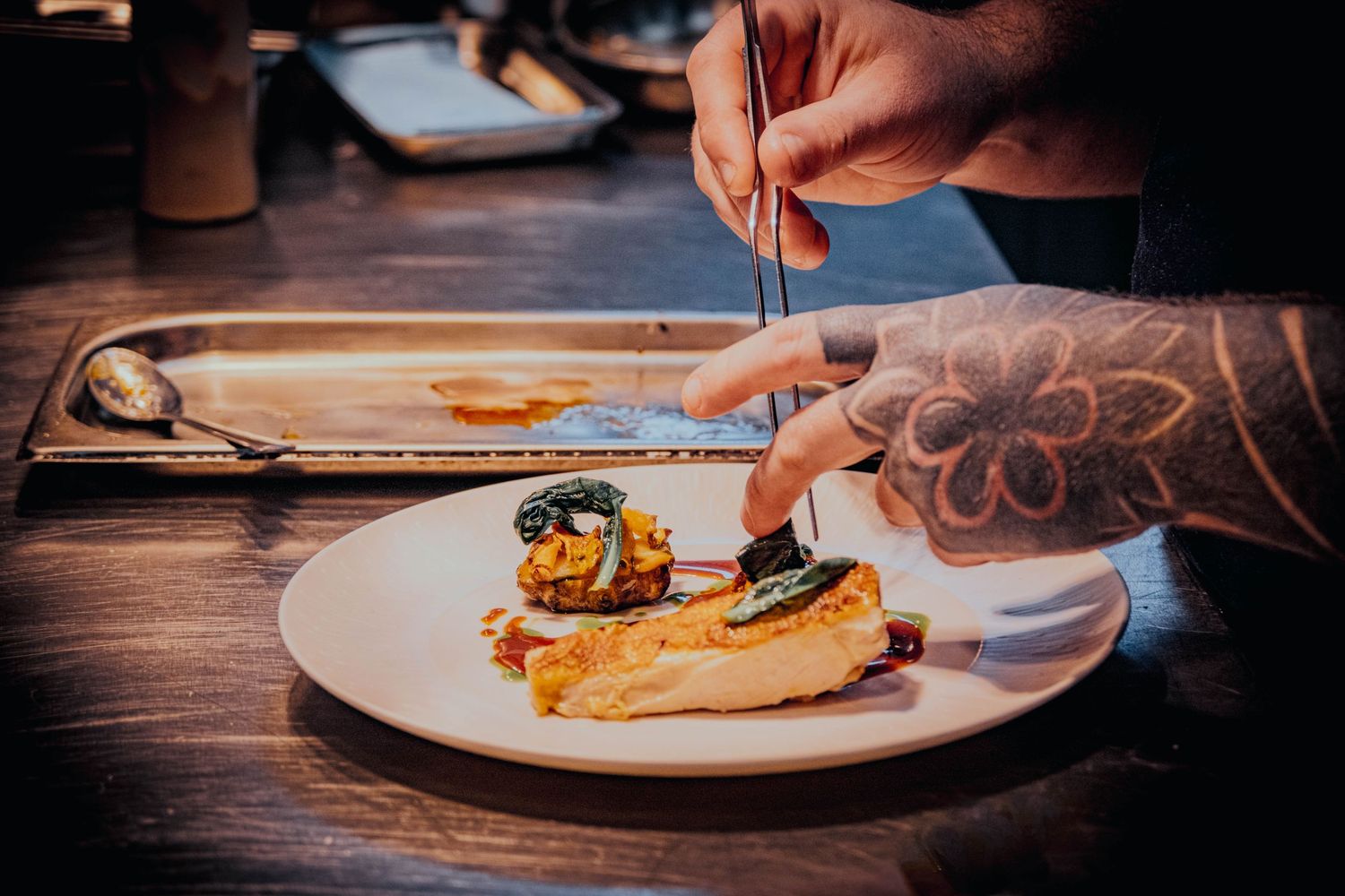 A talented chef plating a delicious fish dish in a fine dining restaurant in Ilkley