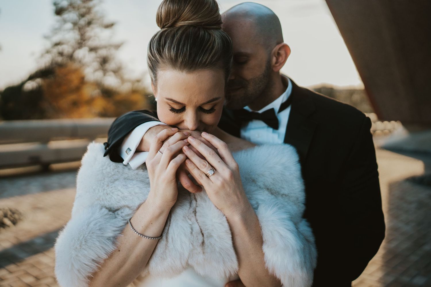 Two people share an intimate moment outdoors during a winter wedding, with one wearing a white fur wrap and formal attire.