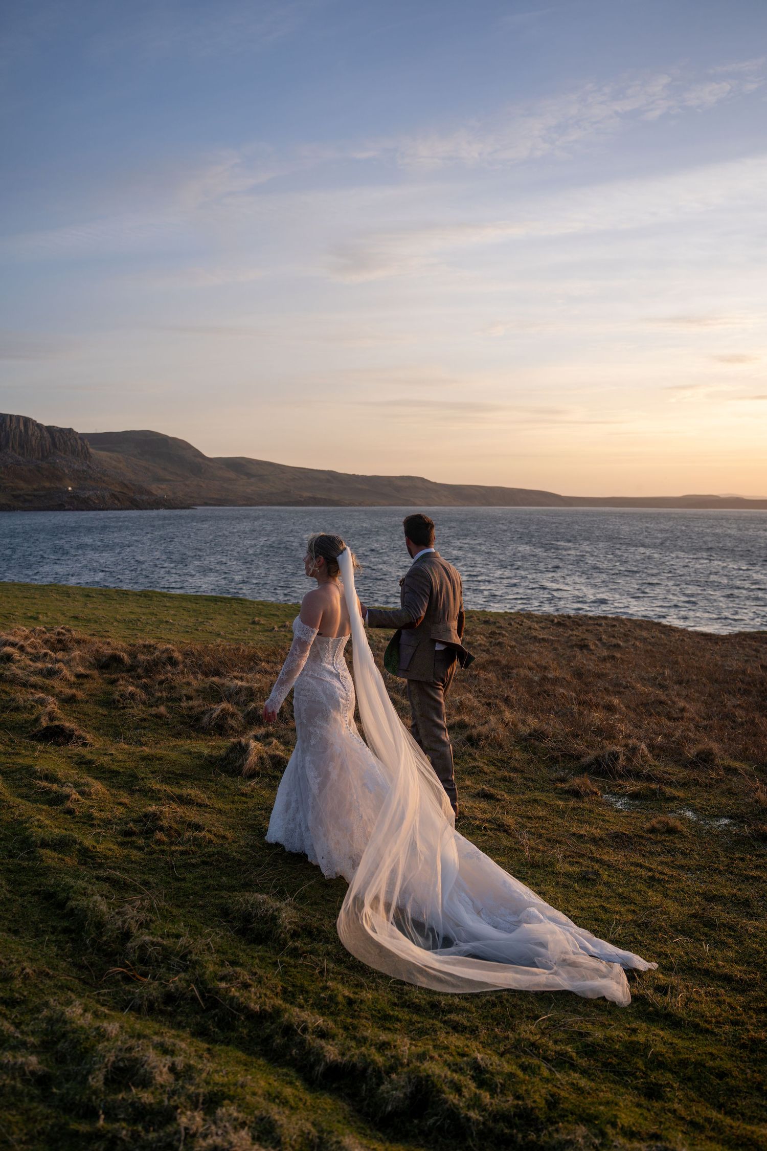 ride and groom walking hand in hand at sunset on Isle of Skye, Scotland, romantic and natural wedding photography capturing authentic love a