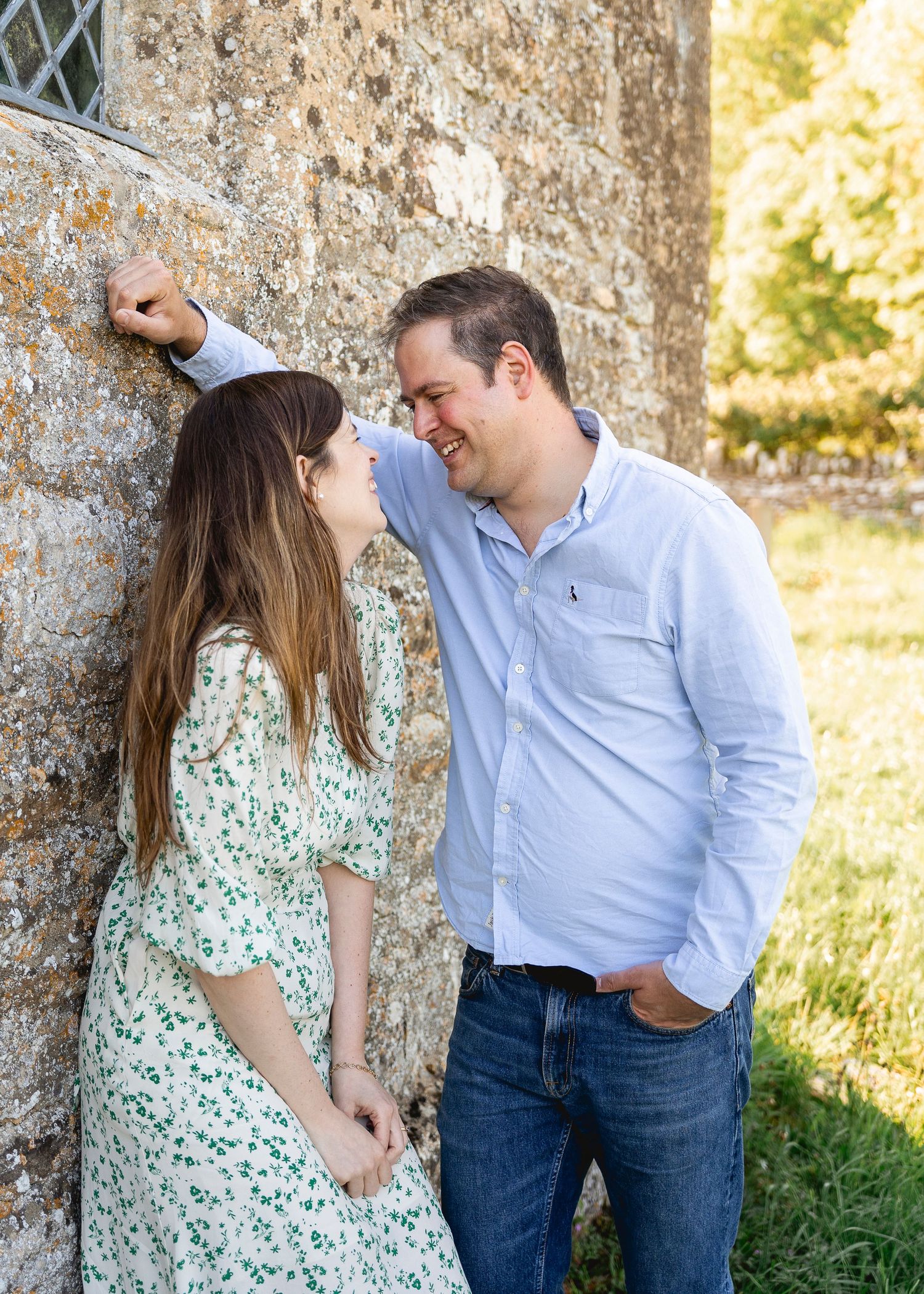 couple perching by the church wall smiling at each other, man hovering over her ready to kiss her