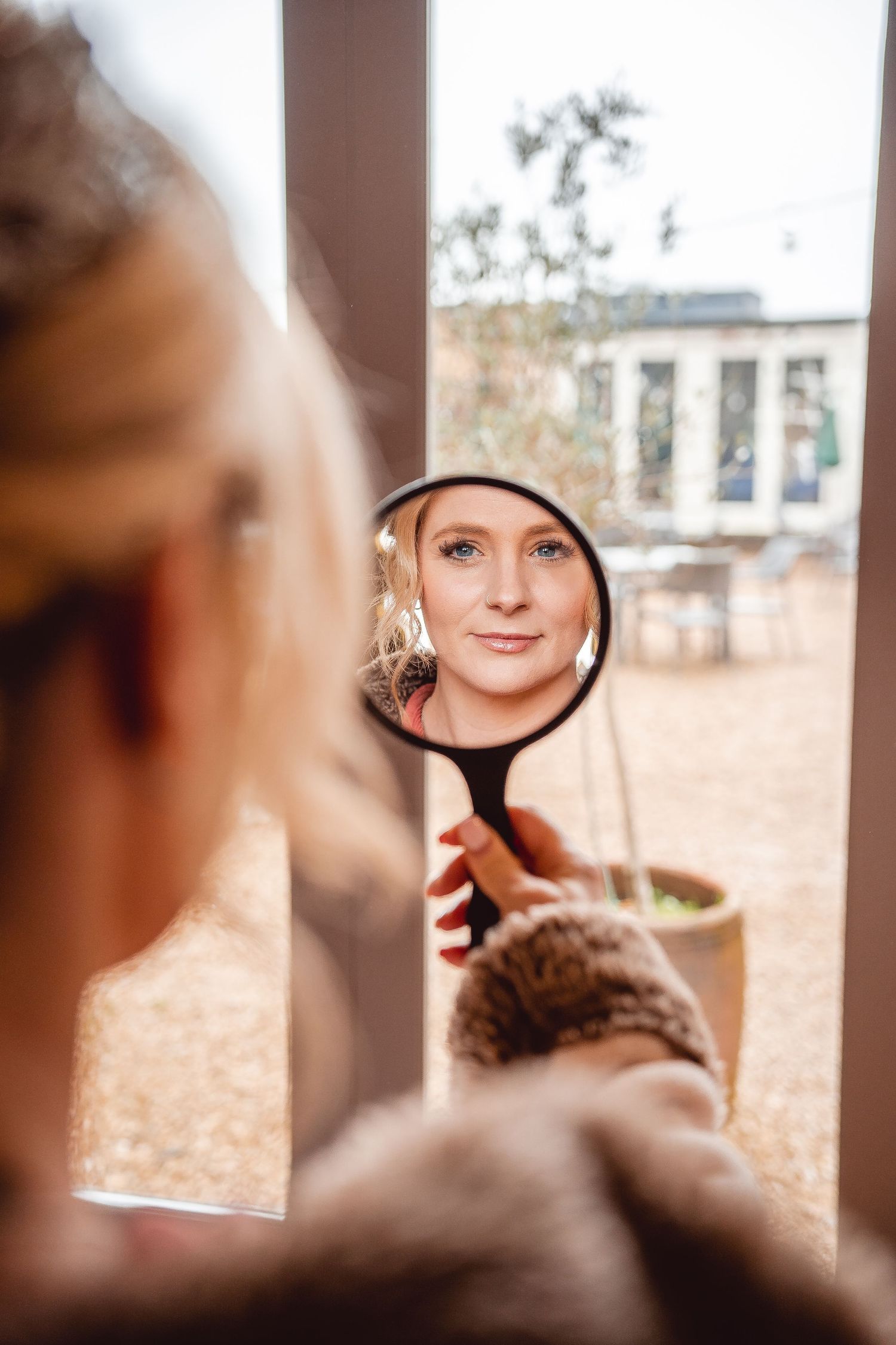 bride looking in a handheld mirror - shot of the reflection