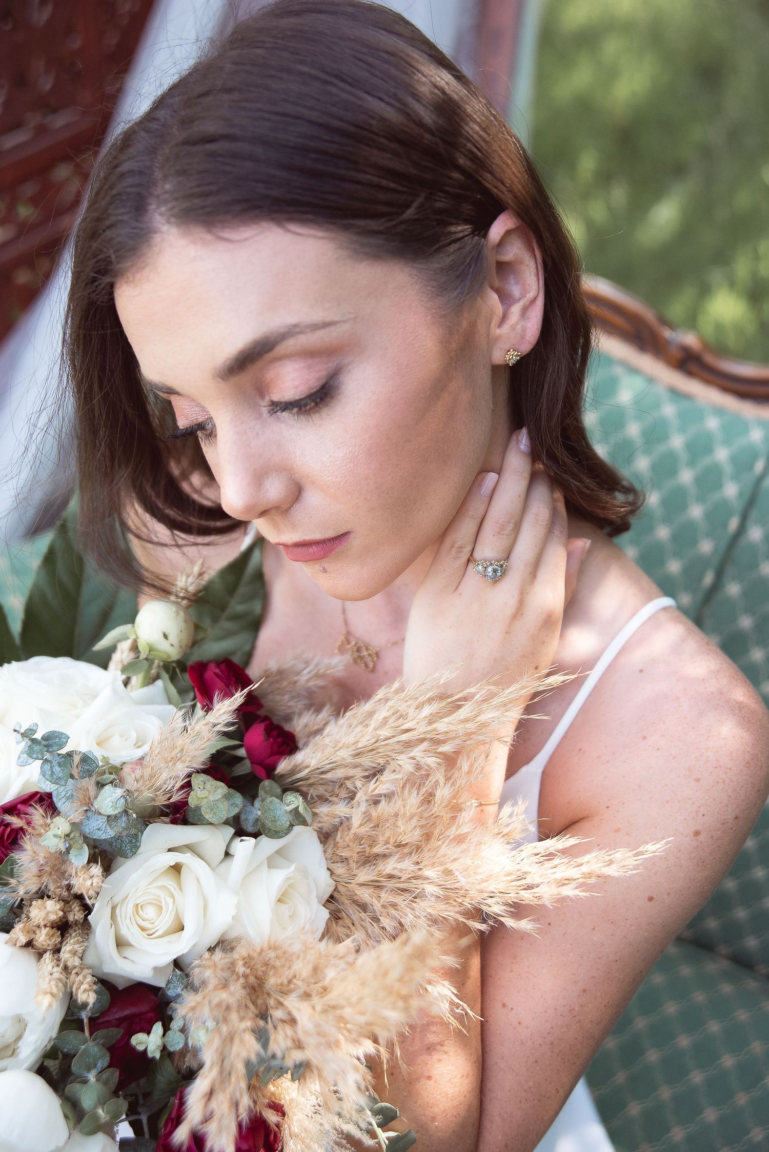 A romantic bridal portrait showcasing a delicate bouquet with white roses and burgundy flowers.