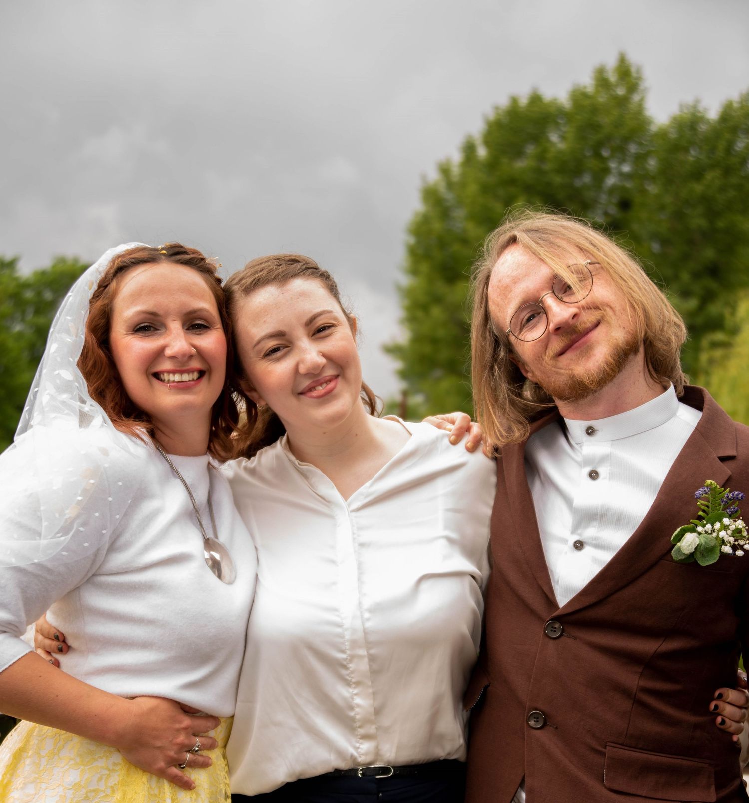 Group photo showing people wearing white shirts and brown attire posing together outdoors.