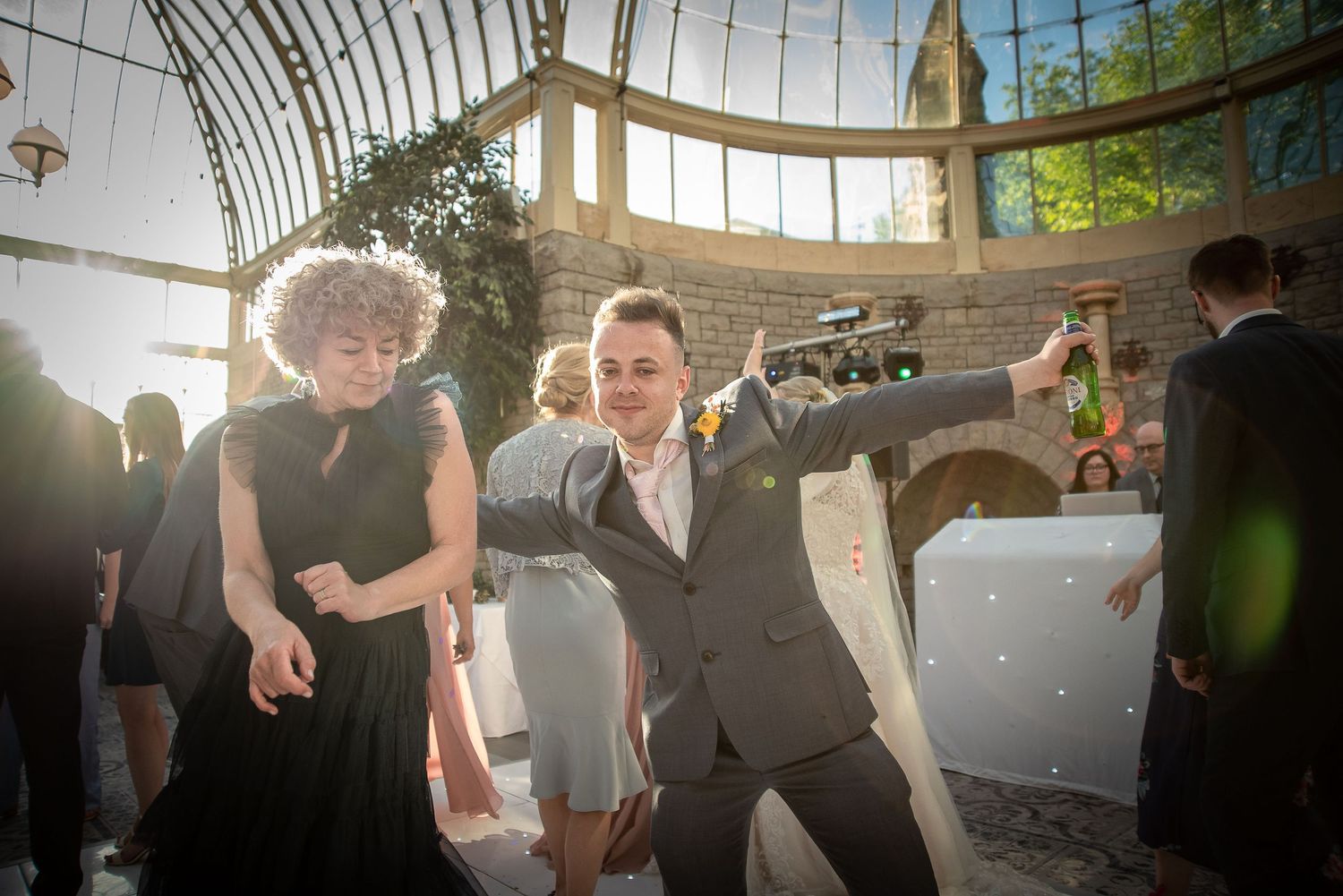 Wedding guests dancing and celebrating on the dance floor under a glass-domed venue.