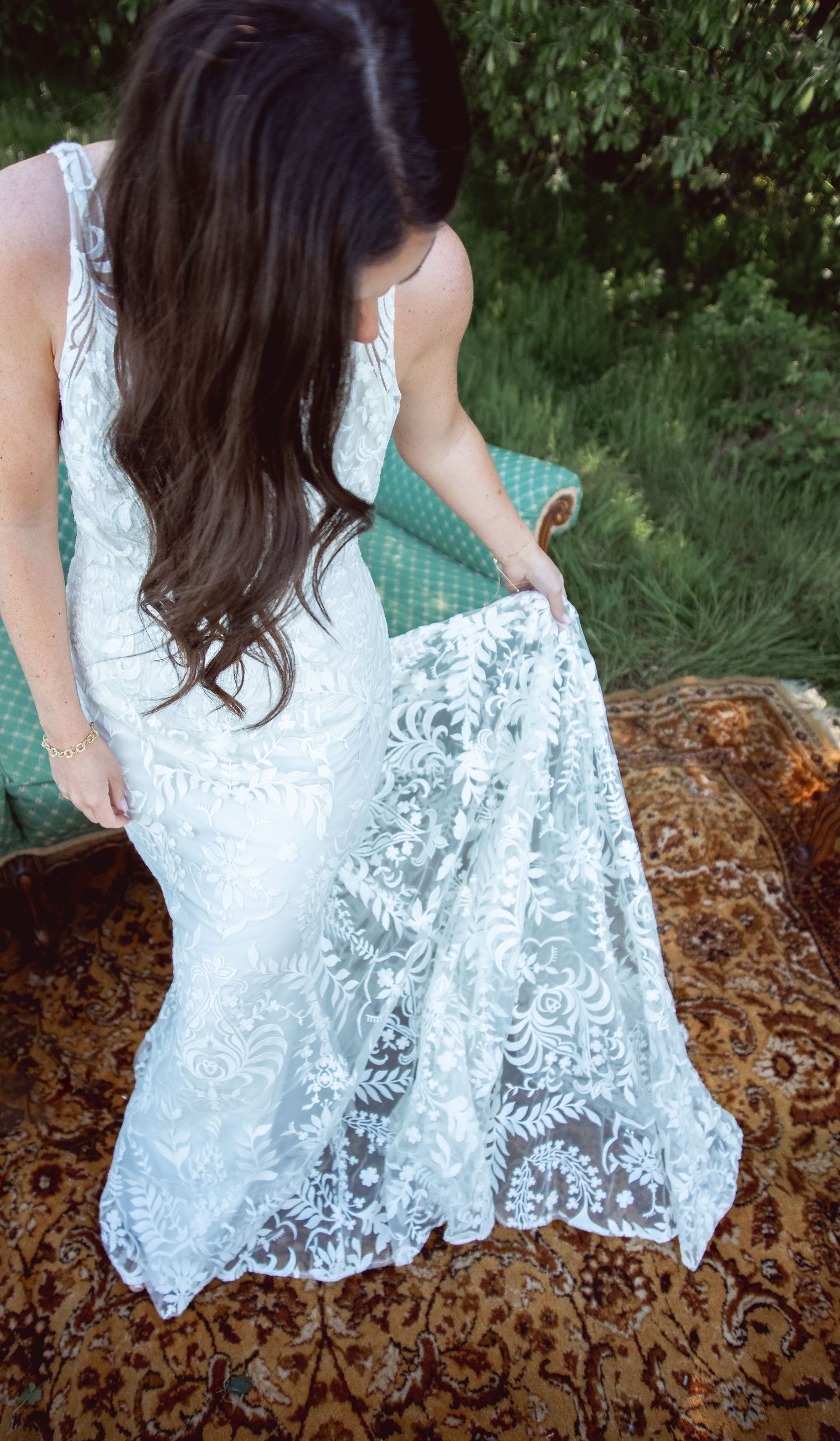 Close-up detail of a white lace wedding dress against a textured brown background.