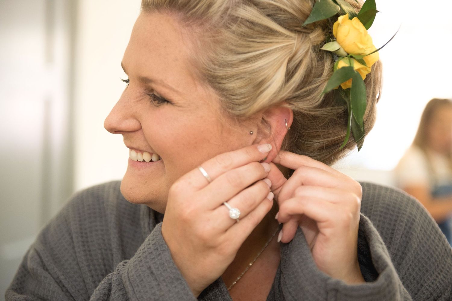 Close up of Bride putting on earrings with yellow flower in her hair