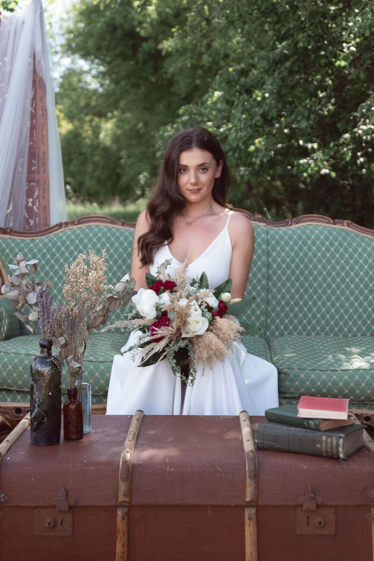 A wedding scene with vintage mint sofa and floral arrangements displayed against a wooden backdrop.