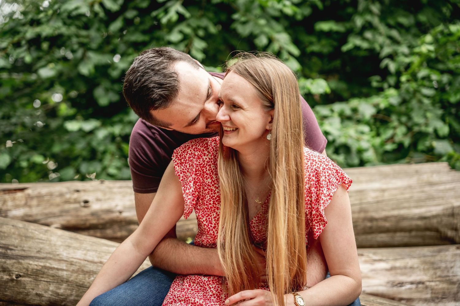 close up of man kissing woman on the cheek as he embraces her from behind