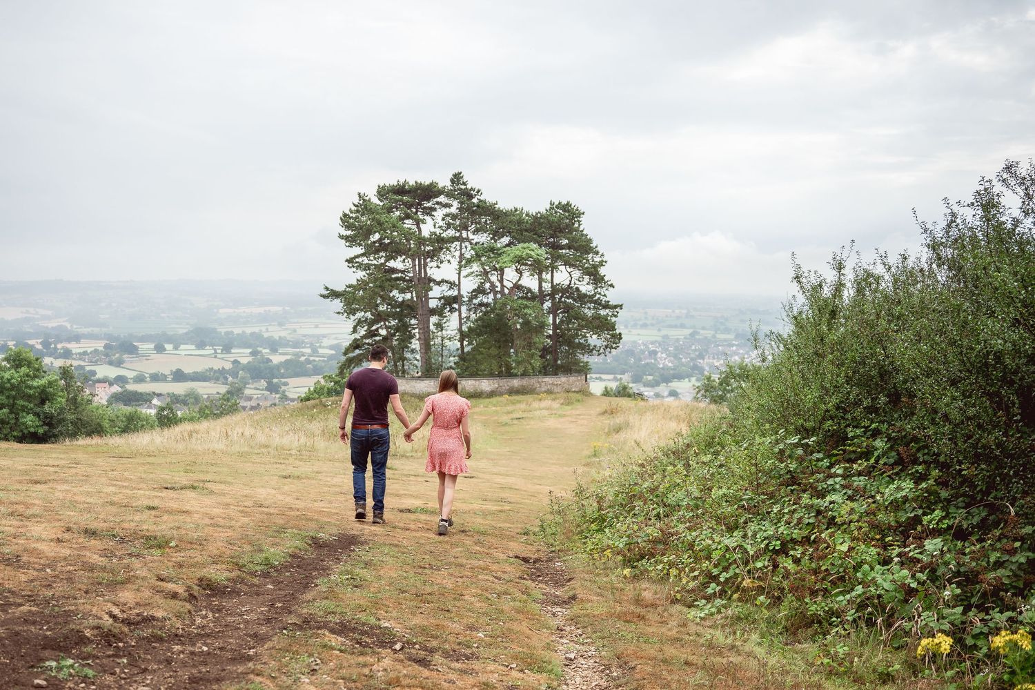 Couple holding hands walking towards trees in the distance