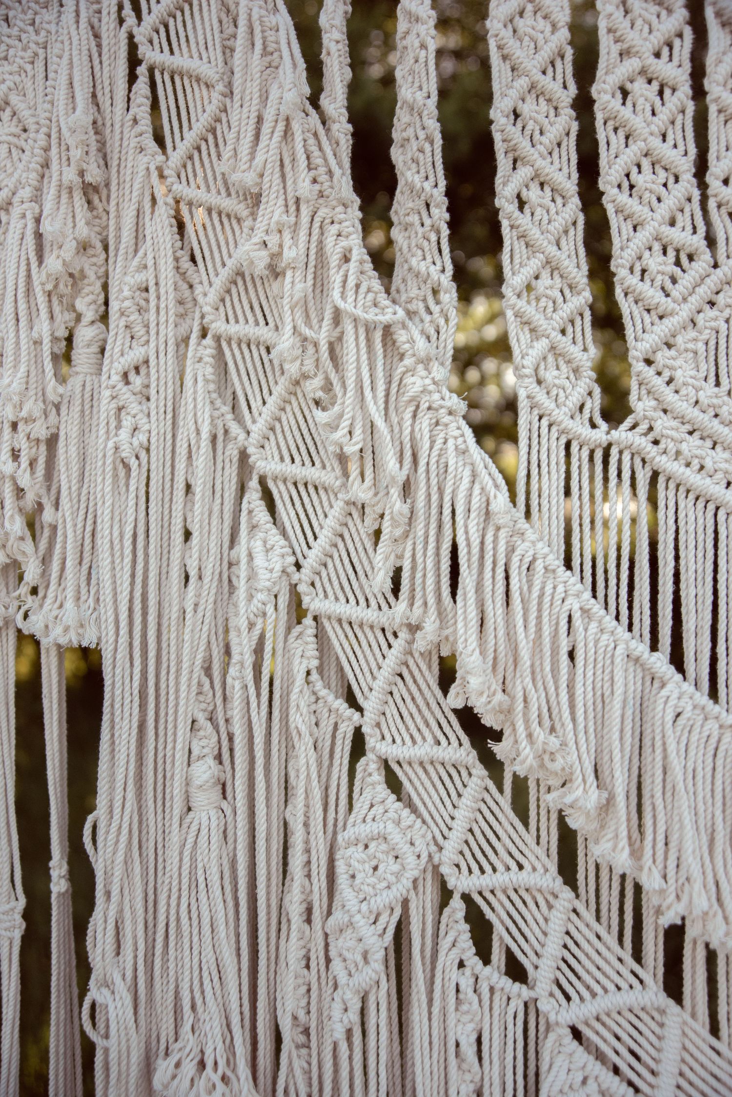 Detailed close-up of intricate white macrame knots and patterns forming a decorative wall hanging.