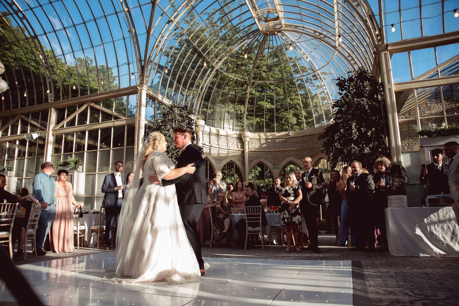 Wedding couple shares their first dance under a stunning glass conservatory ceiling.
