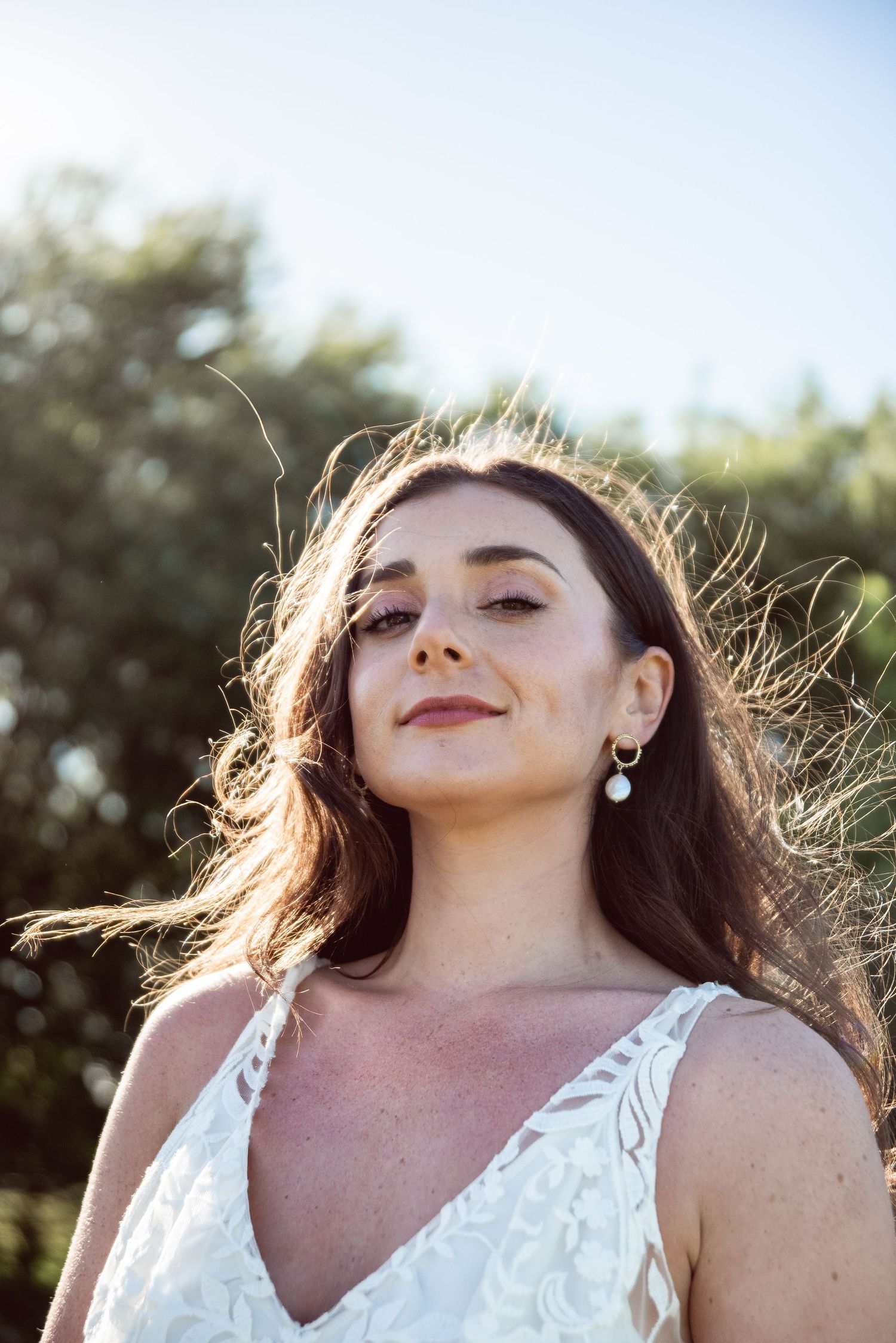 Ethereal backlit portrait in a white lace dress with sunlight creating a dreamy glow.