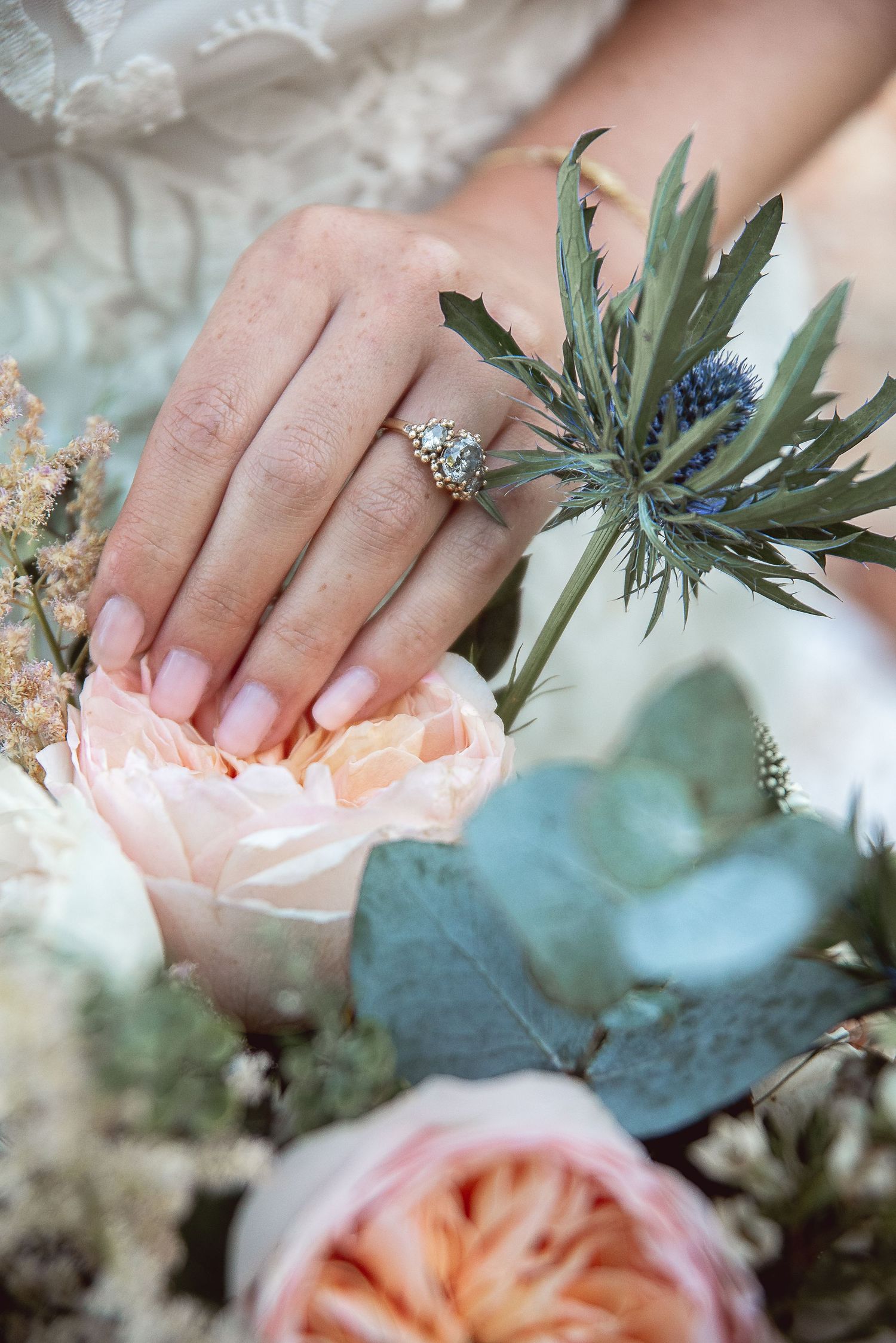 Delicate hands hold a soft peach rose bouquet with eucalyptus accents.