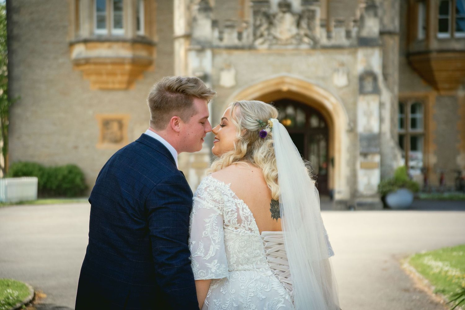 A tender wedding moment captured outside a historic stone building with Gothic architecture.